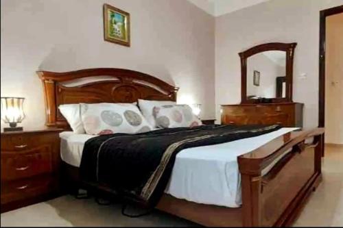 una camera da letto con un grande letto in legno e uno specchio di Charmante location ensoleillée a Alger