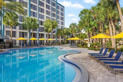 a swimming pool with chairs and umbrellas in front of a building at Delta Hotels by Marriott Orlando Celebration in Orlando