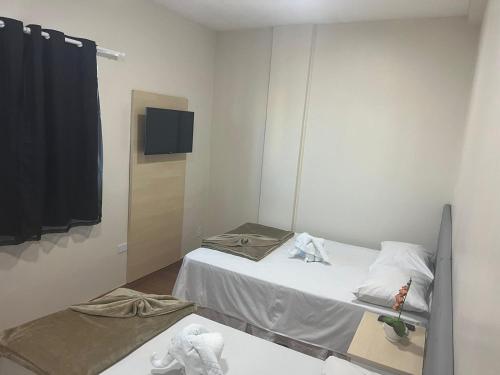 Habitación pequeña con 2 camas y espejo. en Hotel Treviso, en Linhares