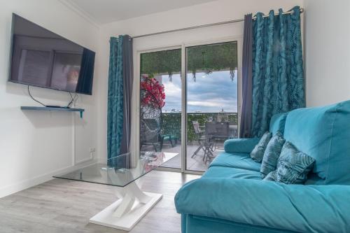 een woonkamer met een blauwe bank en een glazen tafel bij Jardins da Ajuda Apartment in Funchal
