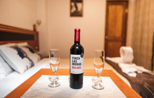 a bottle of wine sitting on a table with two glasses at Escobedo’s Inn Machupicchu in Machu Picchu