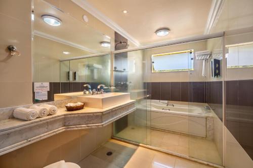 a bathroom with a sink and a shower and a tub at Transoceanico Praia Hotel in Porto Seguro