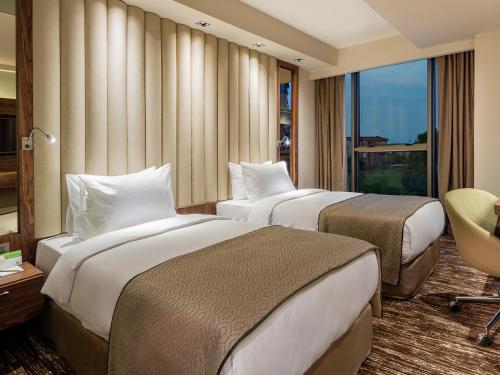a hotel room with two beds and a window at Holiday Inn Antalya - Lara by IHG in Antalya