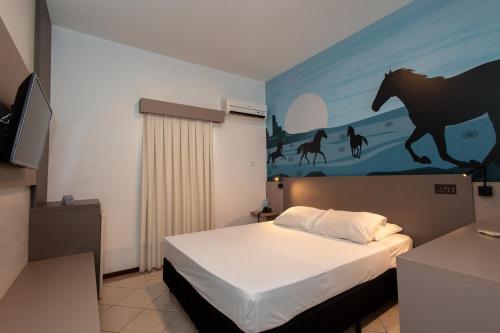 a bedroom with a bed with a horse painting on the wall at ibis Styles Presidente Prudente Portal D'Oeste in Presidente Prudente