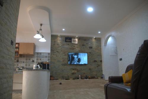 Spacious Appartement in Agadir only for families في أغادير: غرفة معيشة مع تلفزيون على جدار حجري