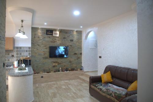 een woonkamer met een bank en een tv aan de muur bij Spacious Appartement in Agadir only for families in Agadir