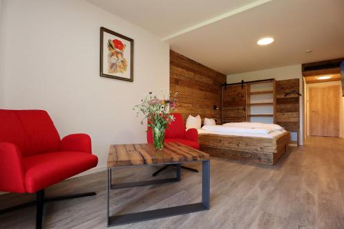 a bedroom with a bed and a red chair and a table at Landgasthof Adler Pelzmühle in Biederbach Baden-Württemberg