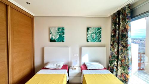 two beds in a room with a window at Ocean view two bedroom apartment in Granadilla de Abona