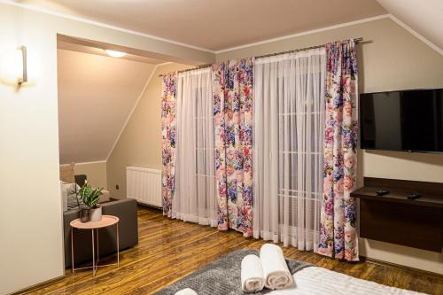 um quarto com uma cama, uma televisão e cortinas em Pensjonat u Słodyczki em Kluszkowce