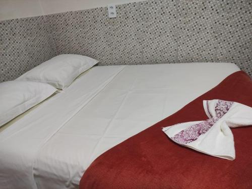 ein weißes Bett mit einer roten Decke und Kissen darauf in der Unterkunft Casa Temporada Espaço Vip in Barra do Garças