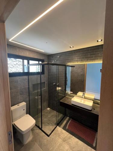 a bathroom with a toilet and a sink and a shower at Suites na Casa da Praia in Ilhabela