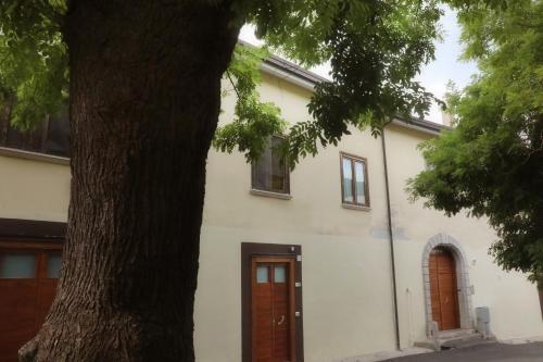 biały budynek z brązowymi drzwiami i drzewem w obiekcie LadimoradiLu' w mieście Piano