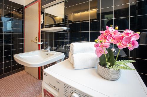 a bathroom with a sink and a vase of flowers on a counter at Innsbruck Garden Residence in Innsbruck