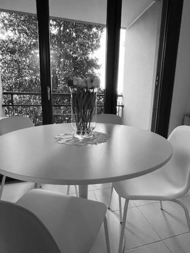 una mesa blanca con sillas y un jarrón encima en Bilocale alle porte di Milano - Magnolia Apartment, en Sedriano