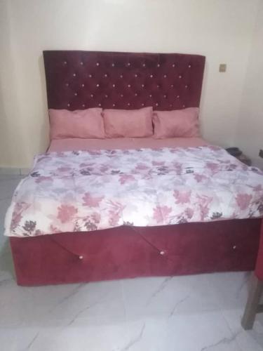 a large bed in a bedroom with a red headboard at Marcopolo Hotel in Makurdu