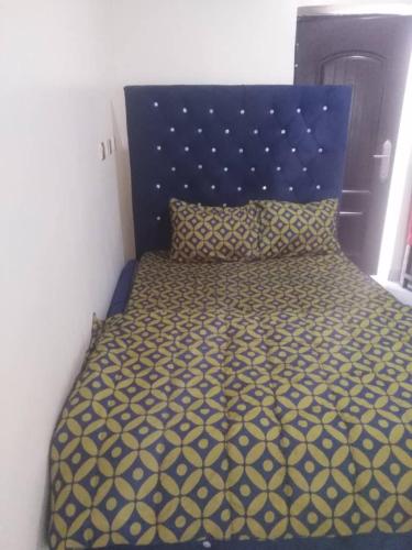 a bed with a blue headboard and a yellow and white bedspread at Marcopolo Hotel in Makurdu