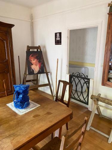 ein Esszimmer mit einem Tisch und einem Gemälde eines Kindes in der Unterkunft Two Bedroom House At La Clayette City Center in La Clayette