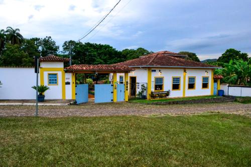 a small yellow and white house with a yard at Pousada Vila Cocais in Cocais