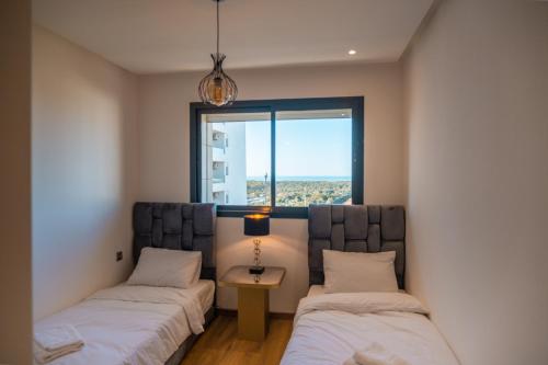 twee bedden in een kamer met een raam bij Appartement luxueux Prestigia in Rabat
