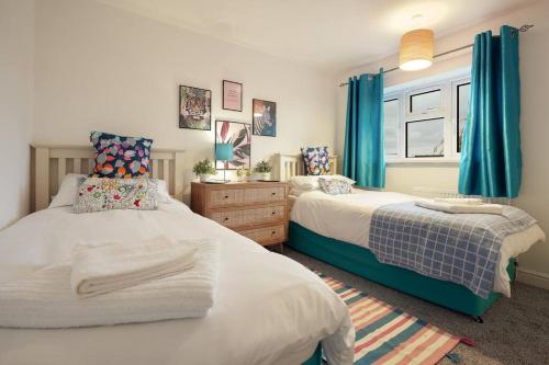 a bedroom with two beds and blue curtains at North Lincs Cosy Home in Messingham