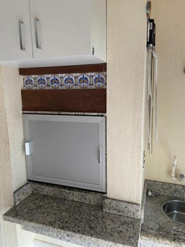 un armario blanco en una cocina con fregadero en Apto Jurerê 2 quartos 400m da Praia, en Florianópolis