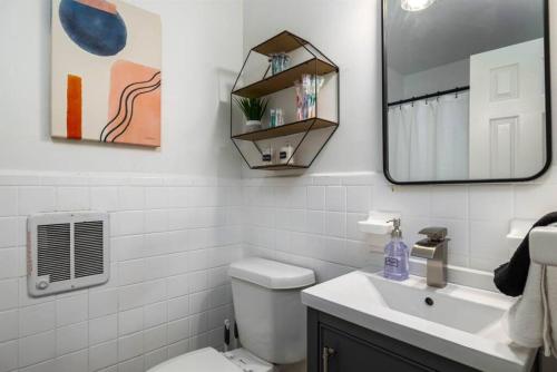 a bathroom with a toilet and a sink and a mirror at Chic 2BR Durham Haven - Walk to Duke in Durham