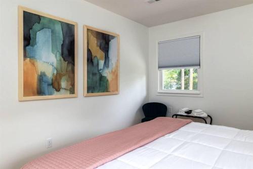 ein Schlafzimmer mit einem Bett und zwei Gemälden an der Wand in der Unterkunft Chic 2BR Durham Haven - Walk to Duke in Durham