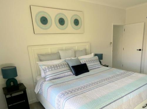a bedroom with a large white bed with pillows at Beach House Yeppoon - ARay at Cooee Bay - Apt A in Yeppoon