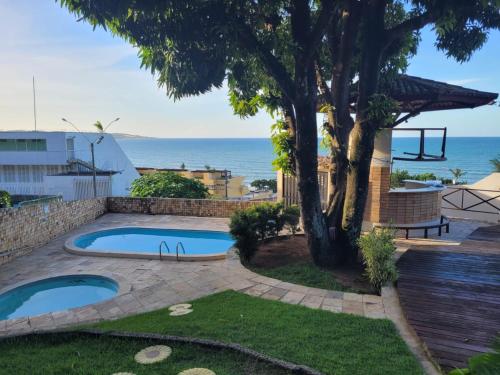 un patio trasero con piscina y un árbol en Apartamentos em Ponta Negra (Natal-RN) com vista para o mar, en Natal