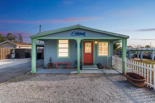 una piccola casa blu con una porta rossa e una recinzione di Flamingo Bay Cottage cottage a Saint James City