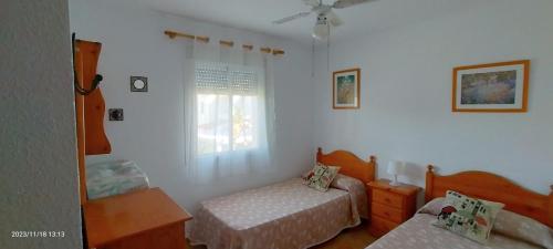 1 dormitorio con 2 camas y ventana en Primera línea de playa casita adosada en Chiclana de la Frontera