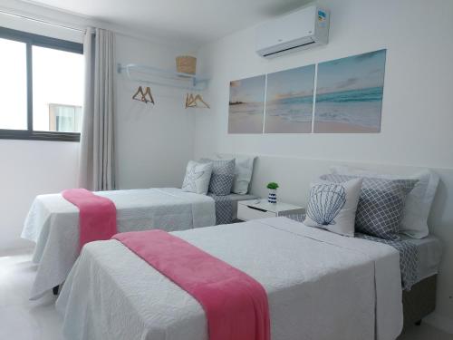 two beds in a room with white walls at Apto à beira-mar em Arraial do Cabo in Arraial do Cabo