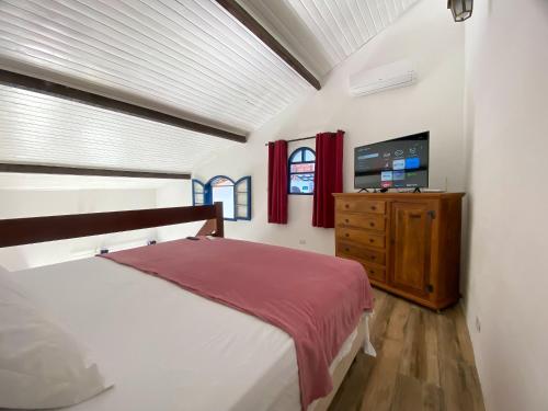 1 dormitorio con 1 cama y vestidor con TV en Villas & Residencial Três Marias à 300 mts do Centro Histórico Paraty en Paraty