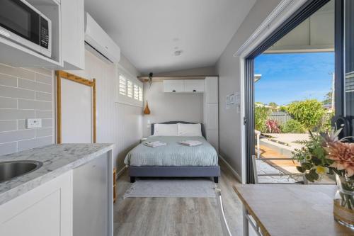 a small bedroom with a bed and a balcony at Tiny House Stays House 1 in Sanctuary Point