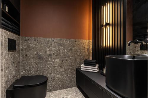 uma casa de banho com uma banheira preta e um lavatório. em Gatsby Luxury Suite By Bobo em Budapeste