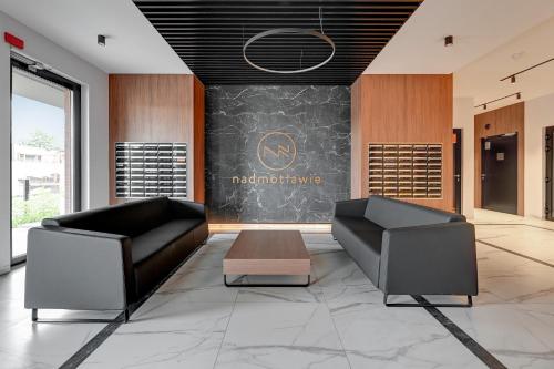 a lobby with two black leather chairs and a chalkboard at Nadmotławie Deluxe 1 Sauna & Siłownia by Grand Apartments in Gdańsk