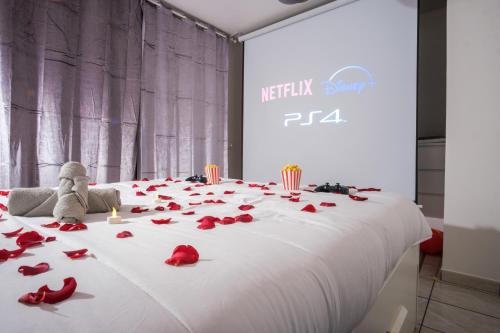 uma grande cama branca com pétalas de rosa vermelhas em Thermal & Home cinéma Disneyland Paris and Terrasse em Lagny