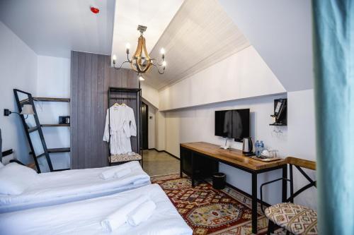 a room with two beds and a desk with a television at Hotel Roshe Gudauri in Gudauri