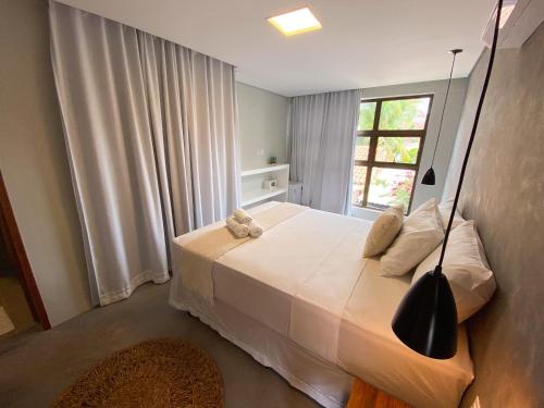 a bedroom with a large white bed with a window at Pousada Baobá in Jericoacoara