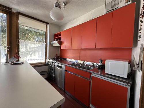 a kitchen with red cabinets and a sink at Appartamento Patascoss in Madonna di Campiglio