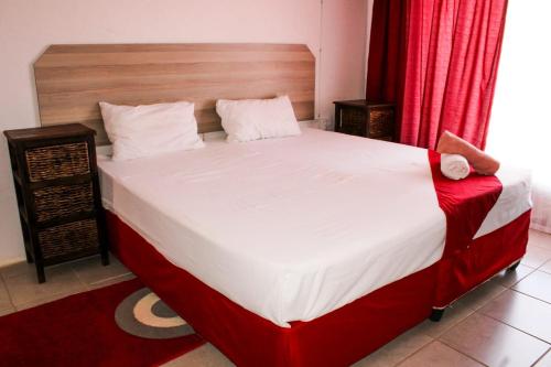 - une chambre avec un grand lit blanc et des rideaux rouges dans l'établissement Godmill guesthouse Taung, à Lethola
