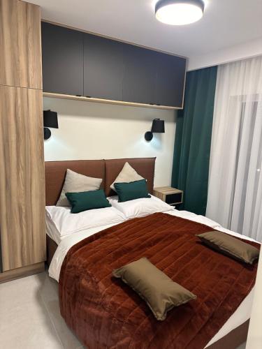 sypialnia z dużym łóżkiem z zielonymi poduszkami w obiekcie Apartamenty Czarne Owce w Szklarskiej Porębie