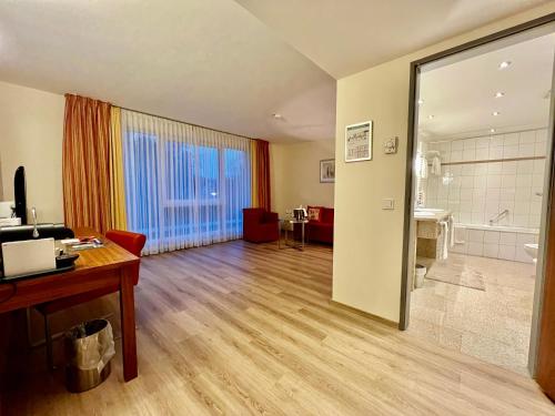 a living room with a desk and a bathroom at Landhotel Krummenweg in Ratingen