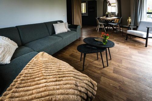 luxe vakantiehuisje - sauna - natuur - strand في Ewijk: غرفة معيشة مع أريكة زرقاء وطاولة
