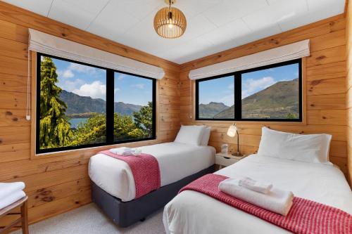 two beds in a room with large windows at Tranquil Heights in Queenstown