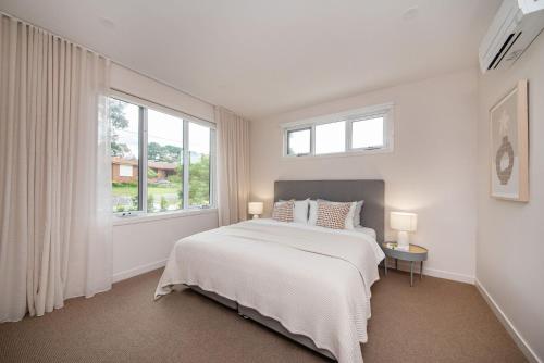 a white bedroom with a bed and a window at Surrey Sunset Sanctuary in McCrae in McCrae