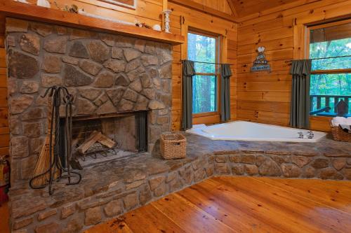 einen Steinkamin in einem Blockhaus mit einer Badewanne in der Unterkunft Cherokee Ridge Cabin Near The Ocoee River in Ocoee