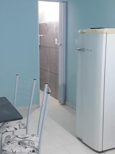 a kitchen with a refrigerator and a chair in a room at Porto apartamento 5 in Porto Seguro