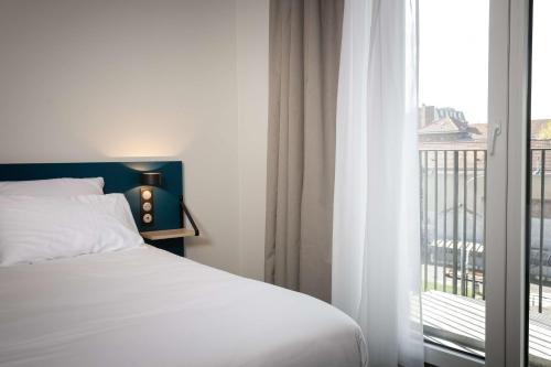 a bedroom with a bed and a large window at Best Western 11BAUER Paris Saint-Ouen in Saint-Ouen