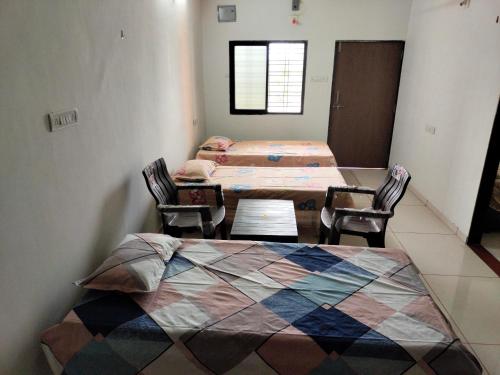 - une chambre avec deux lits et deux chaises dans l'établissement Ashapura Home Stay, à Kevadia
